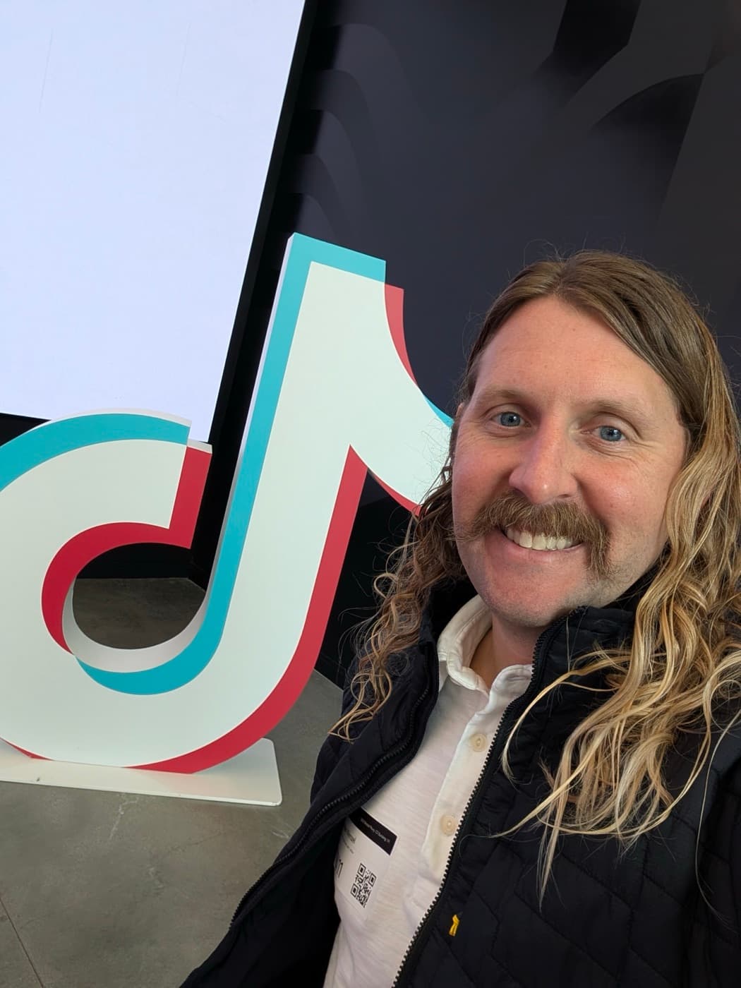 Brendan Wenzel at TikTok's offices, next to a giant TikTok logo